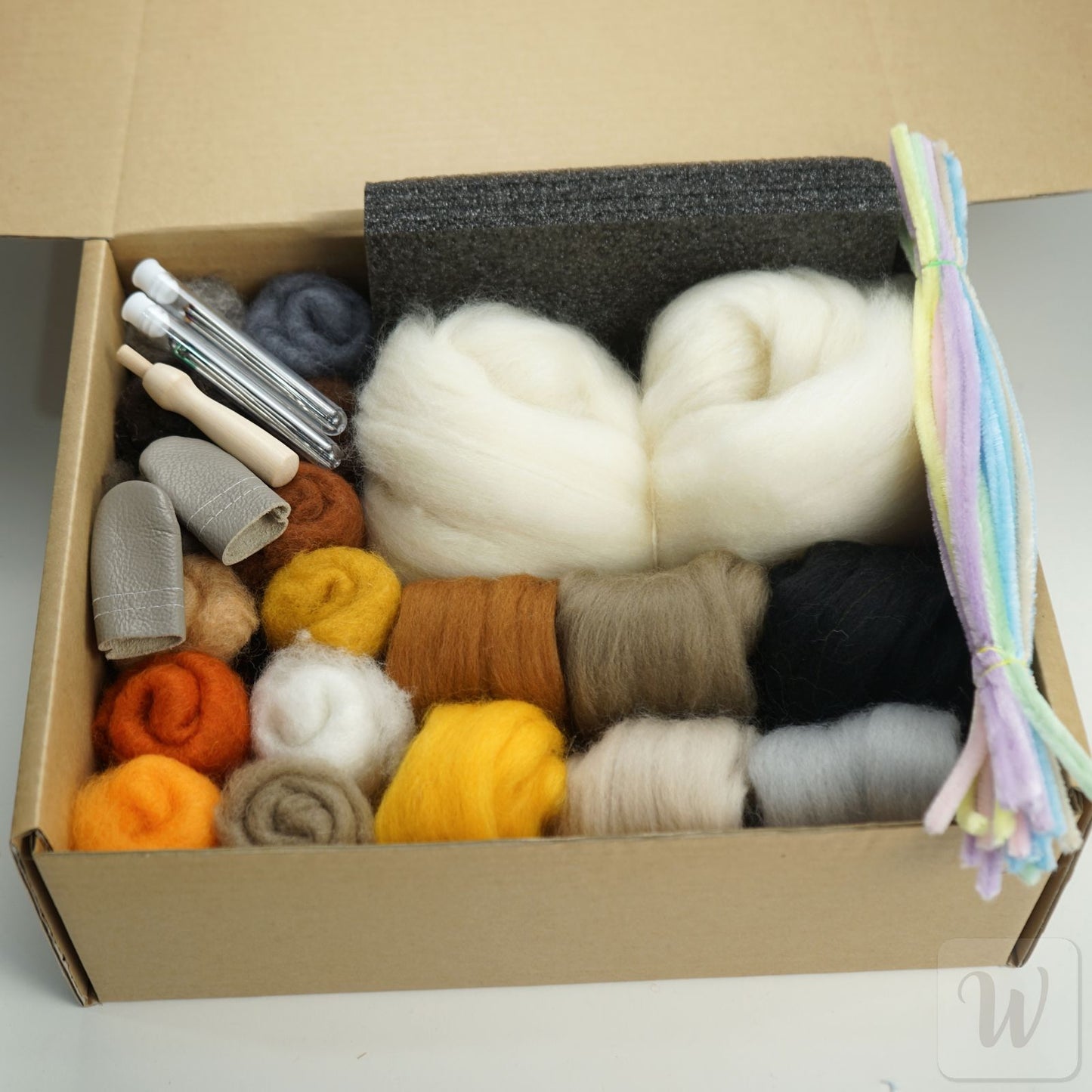 Box containing various colored yarns and knitting tools on a light background